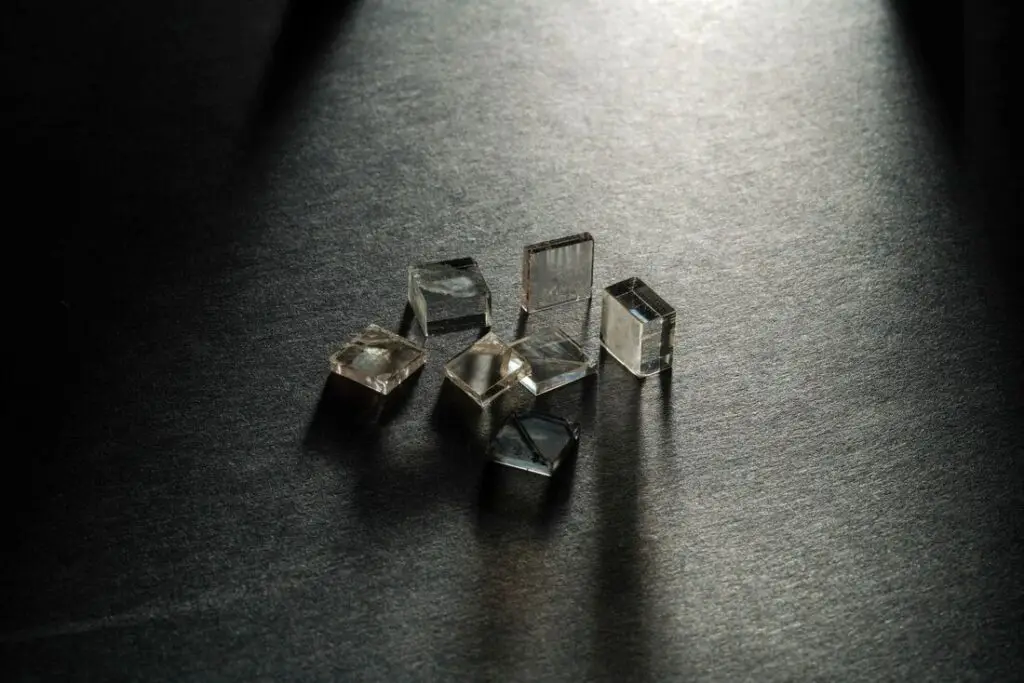Lab-grown diamond crystals and polished samples under directional lighting on dark surface